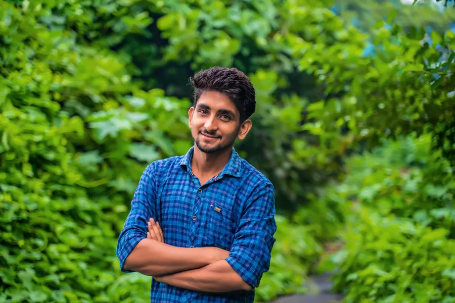 Young man in a checked shirt smiling with arms crossed